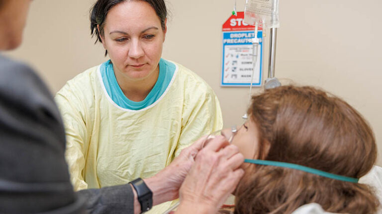 A practical nursing student trains on a medical manikin