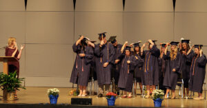 Practical nursing graduates flip their tassel as the program director applauds