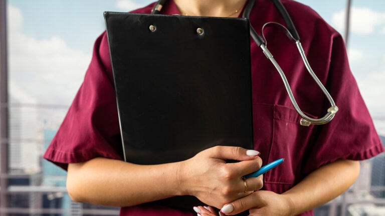 A nurse aide or CNA holding a clipboard