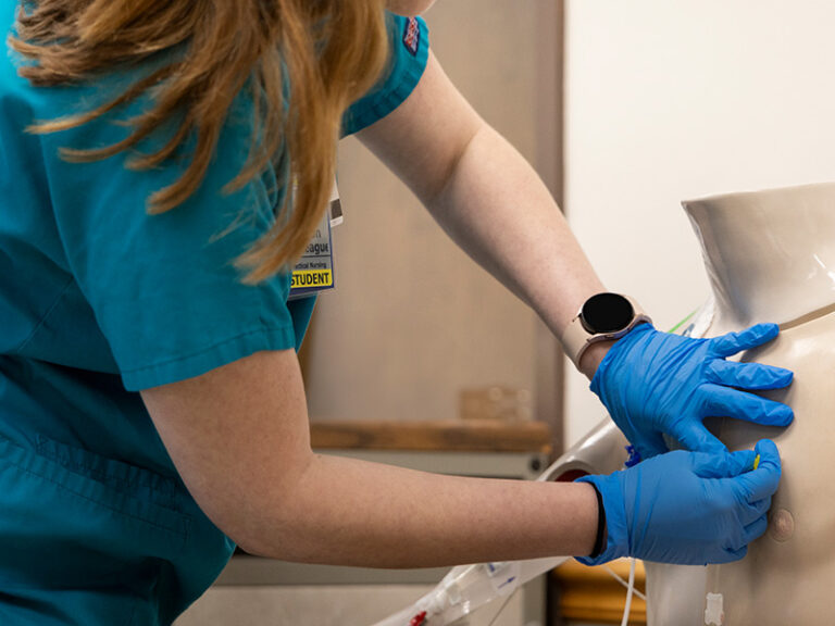 A student nurse working on a dummy torso